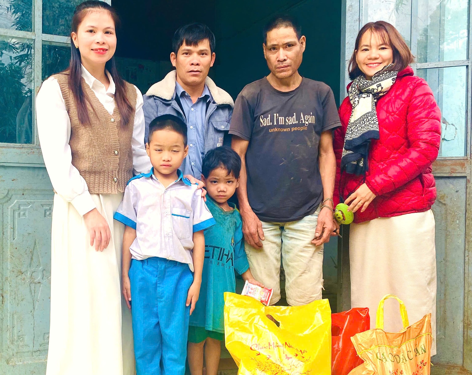 Cô Trần Thị Mỹ Trinh (bên trái, ngoài cùng) thăm và tặng quà gia đình học sinh đỡ đầu Nguyễn Văn Sáng (7 tuổi, người Ca Dong, thôn 5). Ảnh: BÌNH MINH.